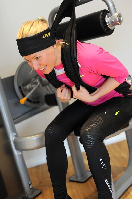 Frau trainiert den Bauch auf einem Gerät in modernen Fitnessraum