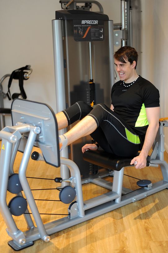Mann trainiert Beine auf einem Gerät im modernen Fitnessraum